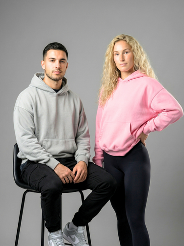 Two people wearing gray and pink hoodies with black pants on a gray background